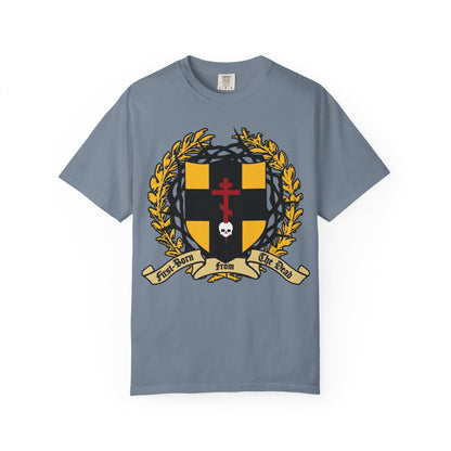 Blue Jean heavyweight cotton unisex t-shirt featuring a heraldic shield with an Orthodox cross piercing a skull, crowned with thorns and adorned by gold laurel. The design includes a banner reading “First Born From The Dead,” powerfully evoking the theme of redemption through His blood as expressed in Colossians 1:18.