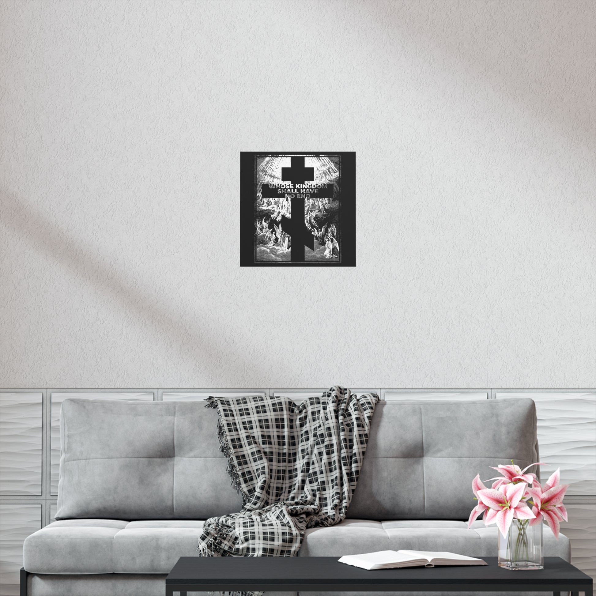 A gray sofa with a plaid blanket, book, and pink flowers sits below the "Whose Kingdom Shall Have No End" Nicene Creed Orthodox art poster, creating a unique space to reflect on Christian faith.