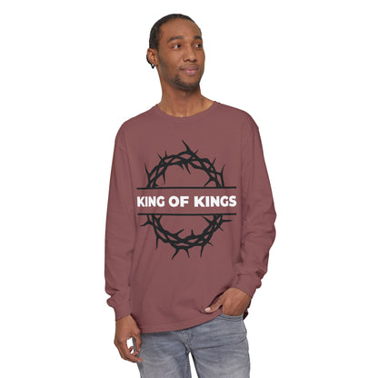 Man wears "King of Kings Crown of Thorns | The King of Glory | Christ is King | Revelation 19:16" Christian cotton long sleeve shirt, featuring a crown of thorns graphic and Bible reference, standing with one hand in pocket.