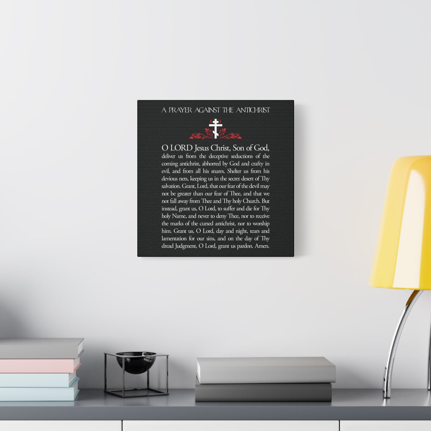 A framed “Prayer Against the Antichrist By Elder Anatoly the Younger of Optina” Orthodox Christian wall art hangs above a modern white desk with a yellow lamp, reflecting the spirit of Christ is King and the Book of Revelation.