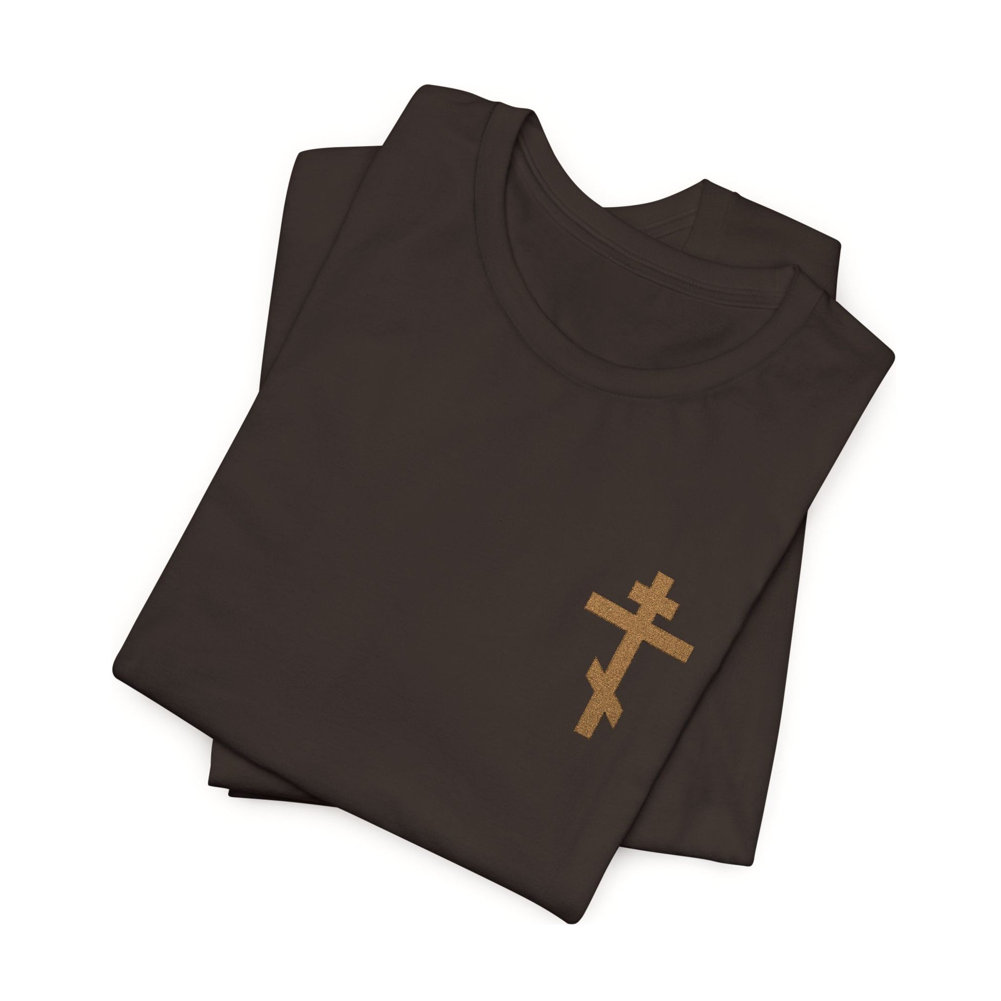 Two folded earthtone t-shirts with a small embroidered Orthodox cross and “May I Never Boast Except in the Cross (Gal 6:14)” on the front. Christian unisex cotton tee.