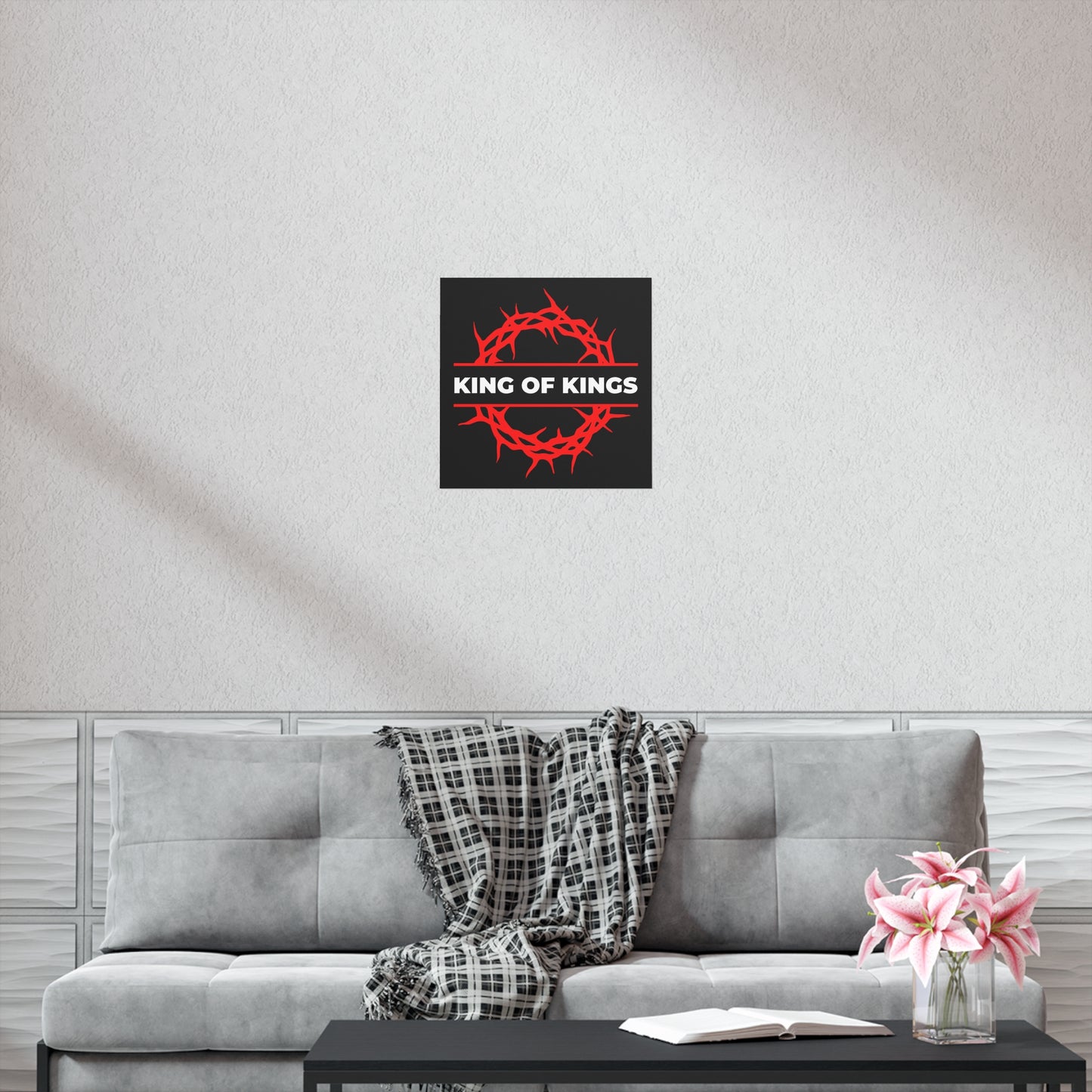 A living room with a gray sofa, plaid throw, pink flowers, and the "King of Kings Crown of Thorns | The King of Glory | Christ is King | Revelation 19:16" Christian Art Poster.