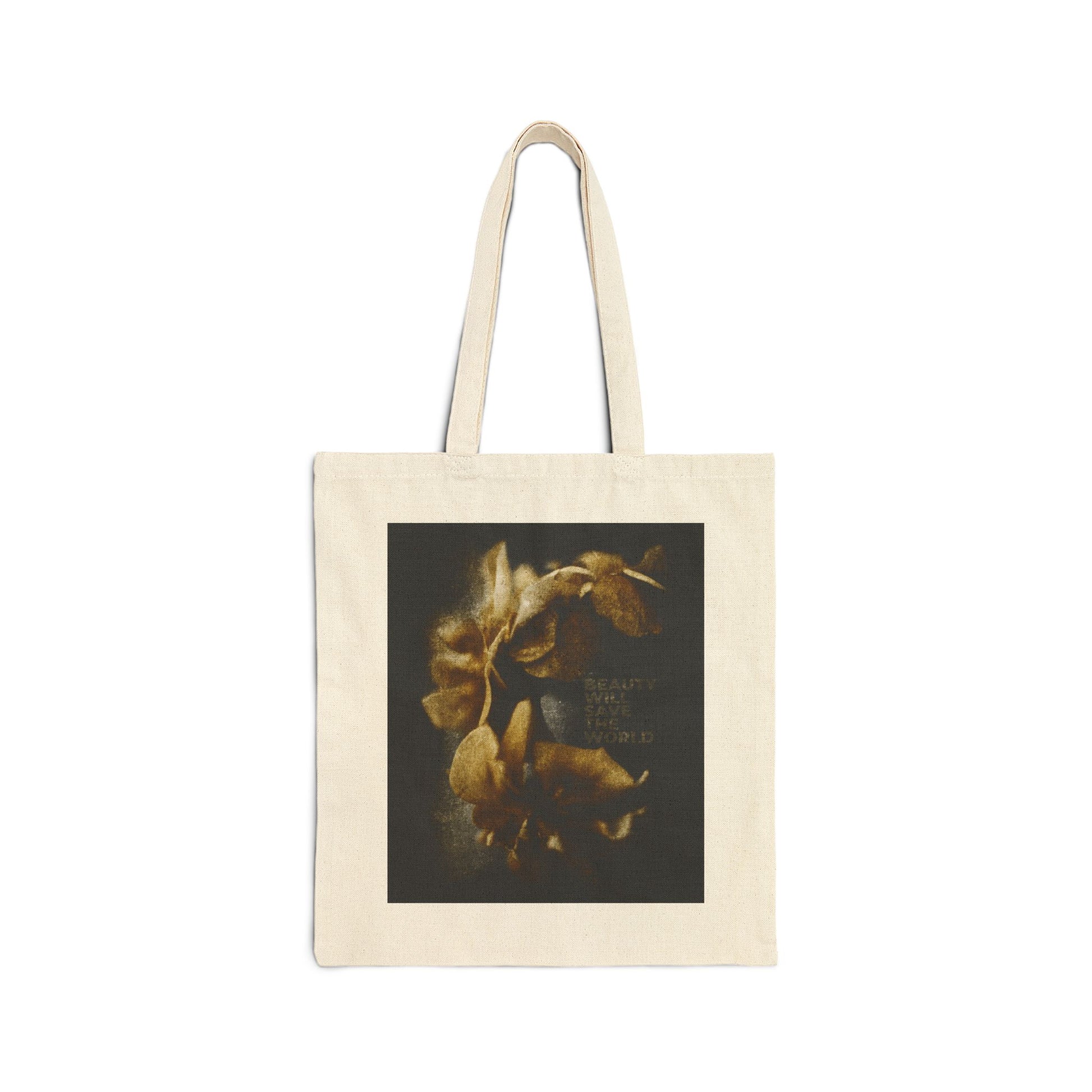 Natural tote bag featuring a dark square photographic print with yellowish flowers and faint text, titled "Beauty Will Save the World." This Christian tote celebrates Jesus Christ as Universal Creator & King.