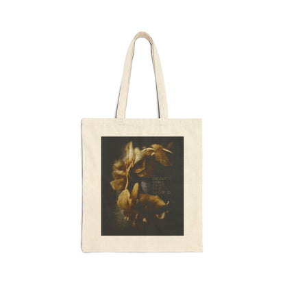 Natural tote bag featuring a dark square photographic print with yellowish flowers and faint text, titled "Beauty Will Save the World." This Christian tote celebrates Jesus Christ as Universal Creator & King.