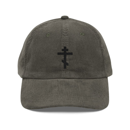 Olive corduroy cap featuring a black embroidered Orthodox TriBar Cross on the front, symbolizing the Weapon of Unseen Warfare Which Makes Demons Tremble.