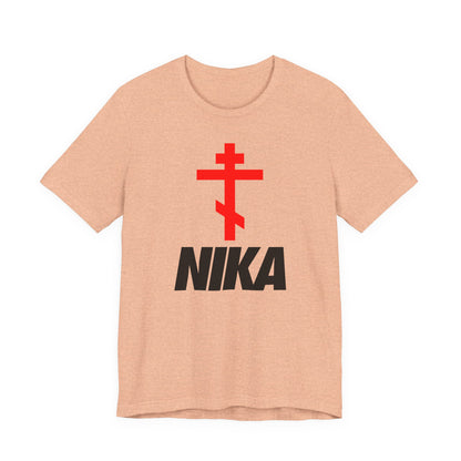 Heather peach t-shirt featuring an Orthodox cross above bold black NIKA text—a minimalist, athletic ascetic design inspired by Jesus Christ Conquers. Christian fashion mashup with a nod to the NIKE logo.
