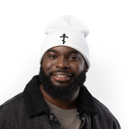 Man smiling in a dark jacket, wearing the "Simple Black Orthodox TriBar Cross | Nail My Passions to the Wood of Thy Precious Cross O Lord" Orthodox Christian embroidered knit beanie against a white background.