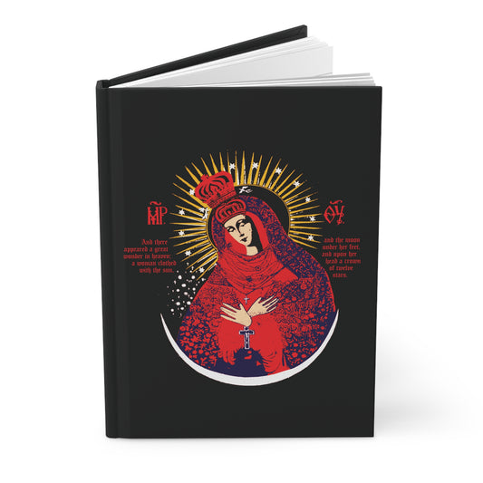 A black hardcover Orthodox Christian journal, "Our Lady the Gate of Dawn Icono-Graphic," features a red, blue & gold design of Theotokos Crowned—Woman of the Apocalypse—adorned with gold rays and red accents on the cover.